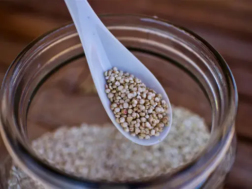Eine Löffelspitze voller Quinoa, dem gesunden Korn, das in einem Glas aufbewahrt wird.