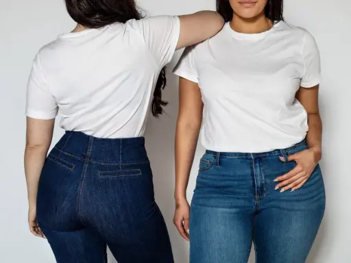 Dwie kobiety w białych T-shirtach i dżinsach na jasnym tle.