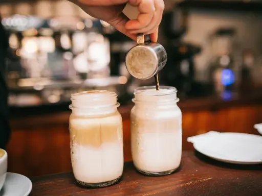 Barista bereitet Latte Macchiato zu. Die Frage "wie viel Kalorien hat ein Latte Macchiato" beschäftigt viele Genießer.