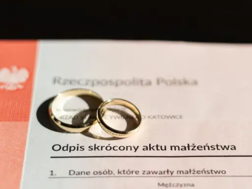 Złote obrączki na odpisie skróconym aktu małżeństwa, symbolizujące zawarty związek.
