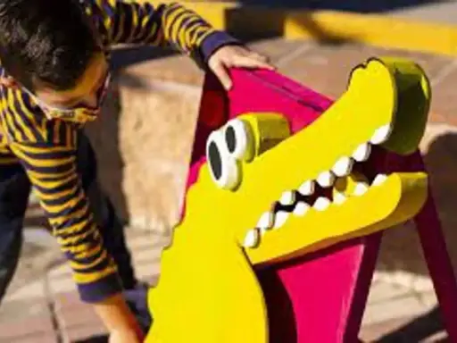 Un niño interactúa con un cocodrilo amarillo de utilería, parte de un espectáculo de teatro infantil en Málaga.