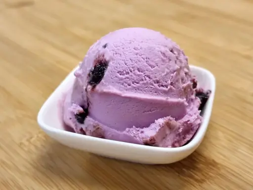 Une boule de glace violette aux fruits, parfaite pour une recette glace amarena maison.