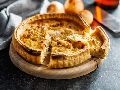 Une part de quiche lorraine, une des spécialités lorraines, sur une planche en bois.
