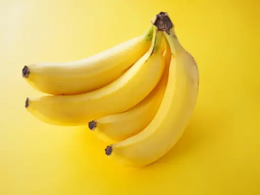 Pęczek żółtych bananów na jaskrawożółtym tle. Idealna przekąska, która dostarczy energii i nie obciąży zbytnio kalorycznie.