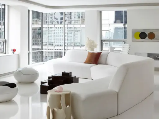 Soggiorno minimalista con divano bianco curvo, sedie futuristiche e tavolini geometrici, un vero esempio di space age design.