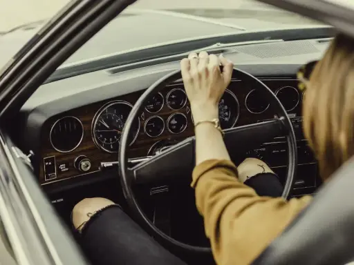 Mujer al volante de un coche clásico. De repente, la dirección asistida dura, dificultando el giro.