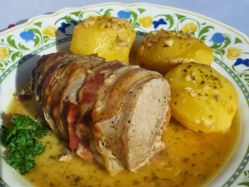 Solomillo al ajillo envuelto en bacon, servido con patatas doradas y perejil fresco. ¡Un plato delicioso!