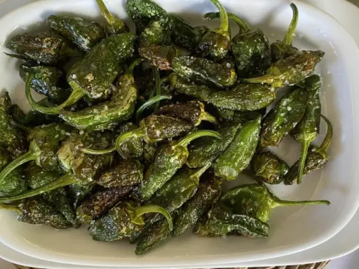 Pimientos de Padrón recién fritos, salpicados de sal gruesa, listos para disfrutar. ¡Así se preparan como freir pimientos de padron!