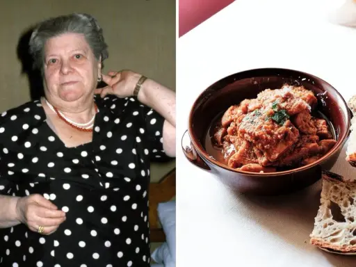 Una donna con un vestito a pois guarda verso la telecamera, accanto a una ciotola di trippa alla romana con pane.
