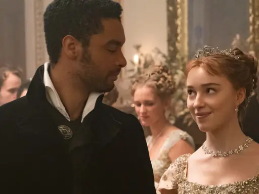 En ung kvinna med tiara och en man i elegant klädsel möts med blickar. Kanske en scen från rollistan i familjen Bridgerton.