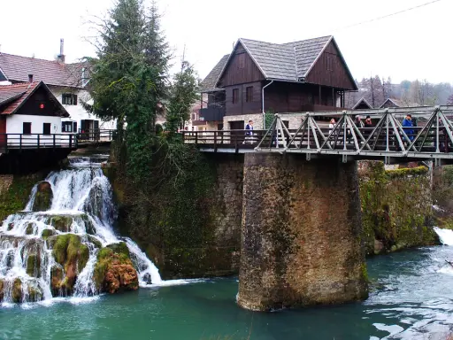 Rastoke, Croazia: cascate e mulini sull'acqua. Un ponte metallico attraversa il fiume, collegando case tradizionali.