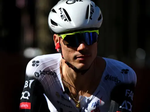 Juan Ayuso, Radsportler im weißen Trikot mit schwarzen Akzenten, trägt einen weißen Helm und eine gelbe Sportbrille.