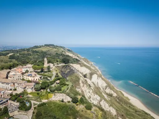 Panoramica aerea di Gabicce Mare, con case arroccate su una collina a picco sul mare Adriatico.