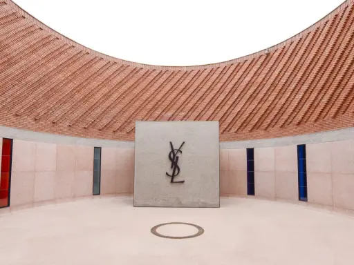 Logo Yves Saint Laurent nel **museo Yves Saint Laurent Marrakech**, con pareti in mattoni e vetrate colorate.