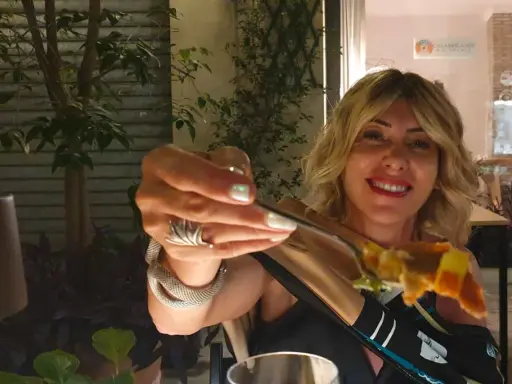 Donna sorridente con un boccone di pizza, in una delle tante rimini restauracje.