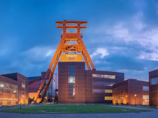 Industrielles Erbe: Der Förderturm des Zollverein 1834 ragt über die beleuchteten Backsteingebäude.