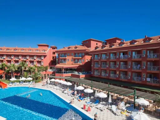 Słoneczny dzień w club side coast. Basen z wodnymi zjeżdżalniami, leżaki i palmy przy hotelu.