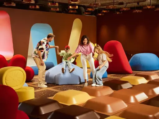 Rodzina bawi się w interaktywnej przestrzeni inspirowanej fabryką czekolady Wedel w Warszawie.