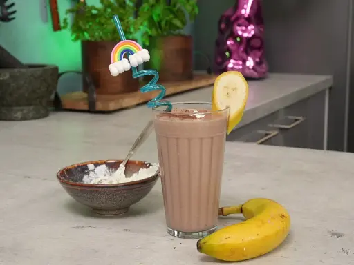 Ein leckerer schoko protein shake mit Banane und einem lustigen Regenbogen-Strohhalm. Daneben eine Schale mit Quark.