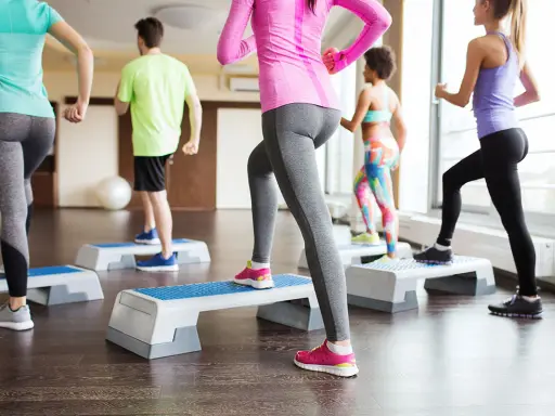 Persone in palestra eseguono attività aerobica a bassa intensità esempi: step-up.