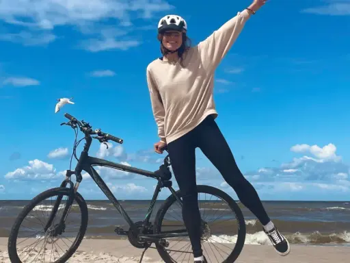 Dziewczyna w kasku na rowerze na plaży. Wspaniała infrastruktura rowerowa nad morzem.
