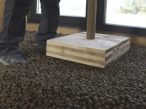 Preparando el suelo para como hacer hormigón con arlita. Se ve una capa de arlita y una base de madera.
