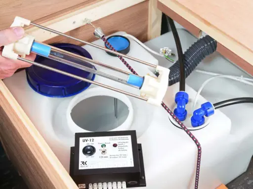 Ein Gerät zur UV-Wasserdesinfektion hilft, das Wasser frisch zu halten. Eine Hand hält eine UV-Lampe über einem Wassertank.