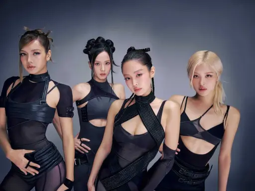 Medlemmar av Blackpink poserar i futuristiska svarta outfits.