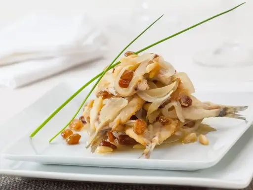 Sarde in saor, un piatto veneziano con sarde, cipolle, uvetta e pinoli, guarnito con erba cipollina.