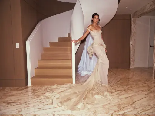 Kendall Jenner in a flowing gown, posing by a spiral staircase, a vision of Met Gala elegance.