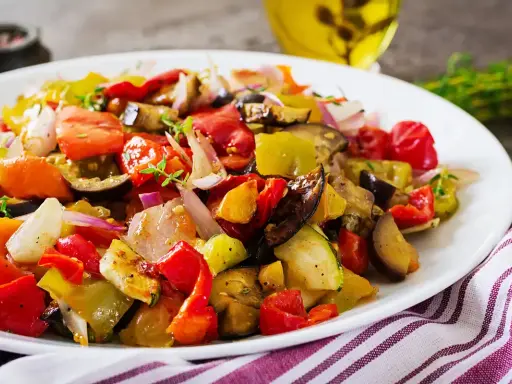 Un piatto colorato di verdure miste, pomodori, melanzane e peperoni, che evoca i sapori dei piatti tipici siracusani.