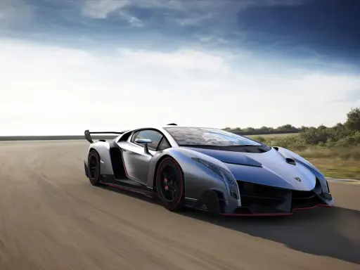 Silberner Lamborghini Veneno Coupé rast auf einer Rennstrecke, die roten Akzente leuchten.