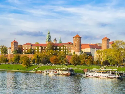 Wawel w jesiennej odsłonie, z łodziami na Wiśle. Poznaj ciekawostki o Krakowie, spacerując brzegiem rzeki.