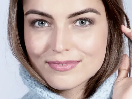 Visage de femme au regard intense, mettant en valeur ses sourcils parfaits. Elle porte un pull bleu ciel.