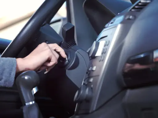 Mano girando la llave de contacto. Es malo tener el coche arrancado mucho tiempo, consume combustible y contamina.