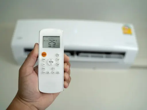 Mano che tiene un telecomando per condizionatore, impostato a 25°C. Il significato di "set temp condizionatore" è la temperatura desiderata.
