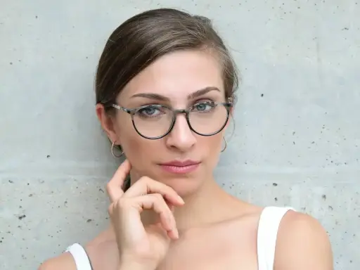 Eleganckie okulary dla szczupłej twarzy podkreślają spojrzenie kobiety.