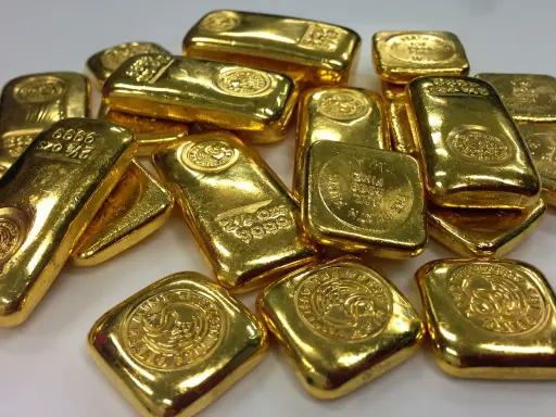 Lingotti d'oro luccicanti, alcuni con incisioni che indicano il peso e la purezza. La domanda "oro 850 quanti carati" è un'ottima domanda per valutare il valore di questi preziosi lingotti.
