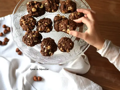 Délicieux cookies au chocolat et noisettes, parfaits pour savoir que faire avec un reste de ganache au chocolat. Une main en prend un.
