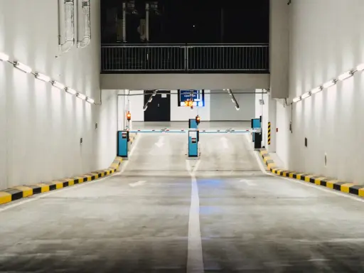 Einfahrt in eine Tiefgarage mit Schranken und Pfeilen, die den Weg weisen. Effizientes Parkraummanagement sorgt für Ordnung.