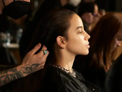 Stylista układa włosy modelki, ukazując olśniewające olaplex efekty: jedwabistość i blask.