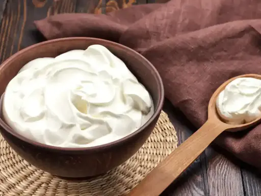 Un bol de crème onctueuse, parfaite pour une crème diplomate, avec une cuillère en bois remplie de cette douceur.