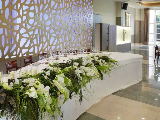 Elegante mesa presidencial boda con arreglos florales blancos y verdes, velas y copas.