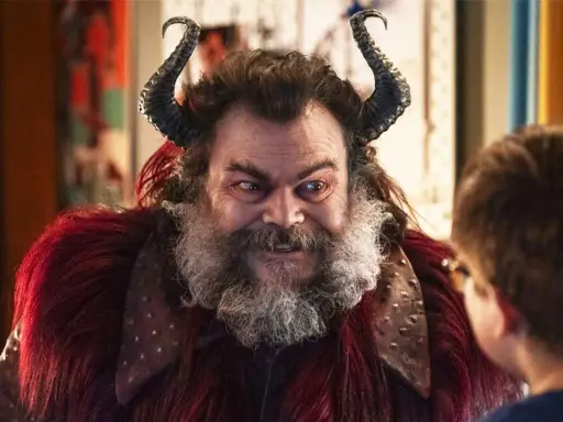Jack Black med horn och rött päls, en karaktär från filmer med Jack Black, tittar på ett barn.