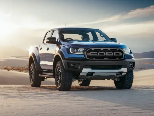 Niebieski Ford Ranger Raptor przemierza piaszczyste wydmy o zachodzie słońca.