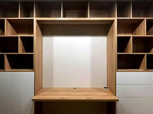 Einbauwand mit Schreibtisch und vielen Fächern. Weiße Schubladen bieten unsichtbaren Stauraum für Ordnung.