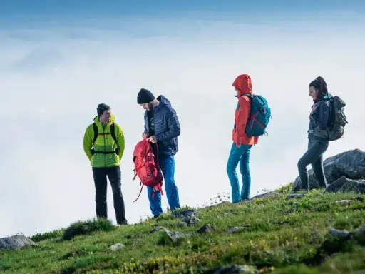 Czterech turystów w górskim krajobrazie, przygotowujących się do wyprawy. To właśnie jest co to trekking – przygoda i odkrywanie.