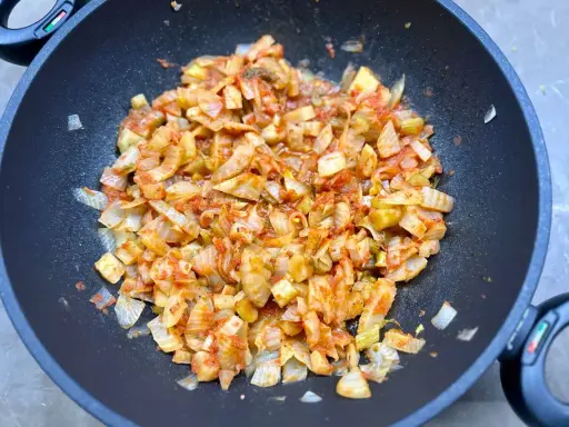 Finocchi in padella, tagliati a pezzi e cotti con pomodoro e spezie, emanano un profumo invitante.