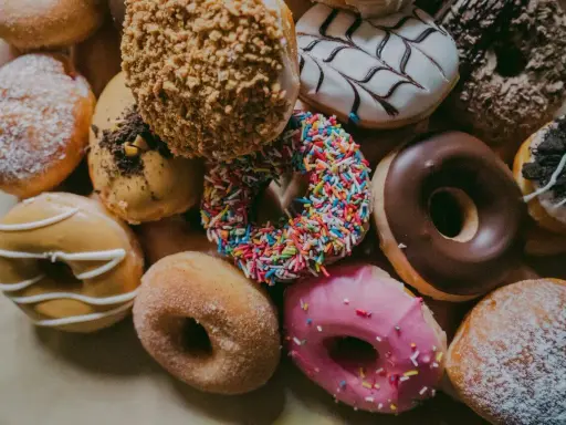 Kolorowe pączki z posypką, lukrem i cukrem pudrem. Zastanawiasz się, ile kalorii ma pączek?