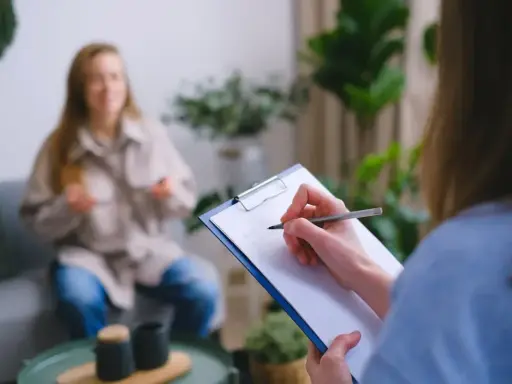 Psycholog notuje podczas sesji. Zastanawiasz się, ile zarabia psycholog policyjny?